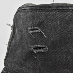 Detailed close-up of distressed denim bucket hat featuring washed black fabric and ripped edges