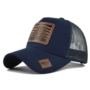 Detail of navy mesh trucker hat featuring embossed lion leather patch and USA map logo