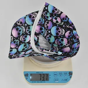 Skull pattern baseball cap being weighed on a digital scale showing a weight of 73.7g