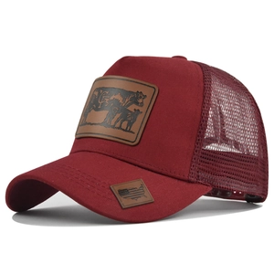 Detail view of maroon trucker hat featuring embossed leather cow patches and mesh back