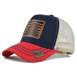 Detail of navy and red mesh trucker hat featuring lion leather patch and side map embroidery