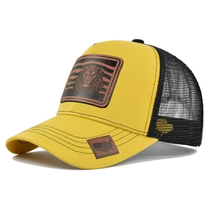 Detailed view of yellow mesh trucker hat with lion patch and leather map patch