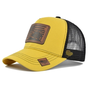 Detail view of yellow trucker hat with embossed leather tractor patch and mesh back