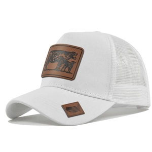 Detailed view of white trucker hat featuring brown leather cow patch and mesh back