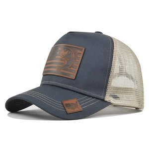 Dettaglio cappello trucker con fronte blu navy, retro a rete e patch in pelle pesce