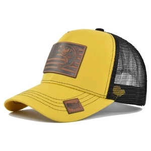 Dettaglio cappello trucker giallo con toppa pesce e bandiera su rete nera traspirante