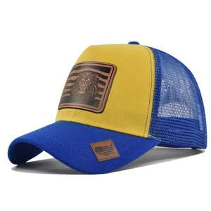 Detail of blue and yellow mesh trucker hat with lion embossed leather patch