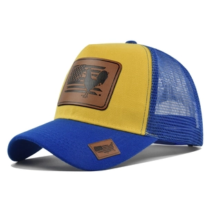 Dettaglio di un cappello trucker giallo con patch a gallo e sfondo bandiera americana