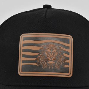Detailed close-up of a brown leather patch featuring a lion head on a black mesh cap