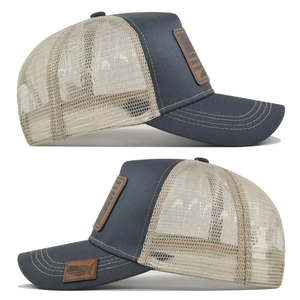 Detail view of trucker hat with navy cotton front and beige mesh showing leather patch