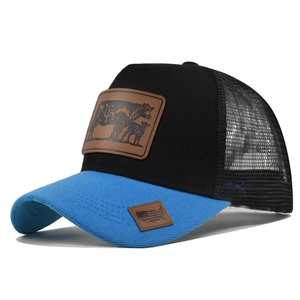 Detail of blue brim and mesh trucker hat with brown leather cow patch on black crown