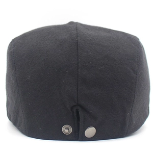 Detail of the back side of a black cotton flat cap with an adjustable metal buckle strap