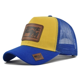 Detail view of yellow trucker hat with leather cow patch and blue mesh backing