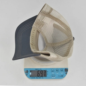 Detailed weight measurement showing a grey and beige mesh trucker hat on a digital scale