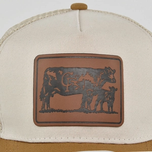 Close-up of vintage mesh trucker hat featuring a cow embossed brown leather patch logo