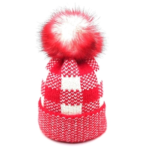 Detailed knit texture of red and white checkerboard beanie with fluffy faux fur pom-pom