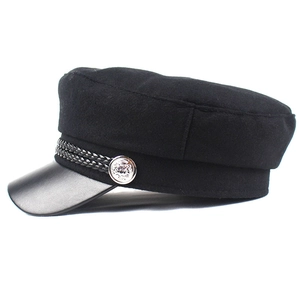 Detail of black wool sailor cap showing faux leather brim and silver crest button