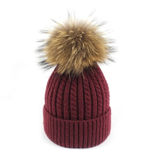 Dettaglio cappello in maglia a trecce rosso scuro con pompon in vera pelliccia