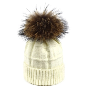 Detalle del gorro de punto texturizado con un gran pompón de piel de mapache de calidad