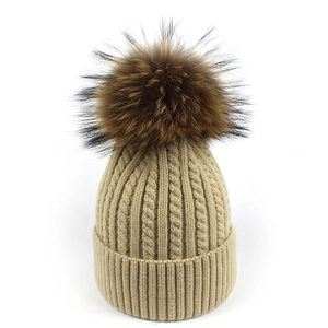 Dettaglio della trama a maglia e del pompon in pelliccia sul berretto in lana di alpaca