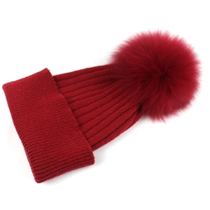 Dettaglio della trama a maglia del berretto rosso con pompon in ecopelliccia e risvolto