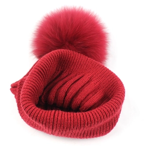 Berretto in maglia rossa con pompon in pelliccia di volpe e coste verticali