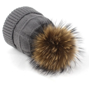 Gorro de punto gris oscuro con un gran pompón de piel de mapache marrón para el invierno