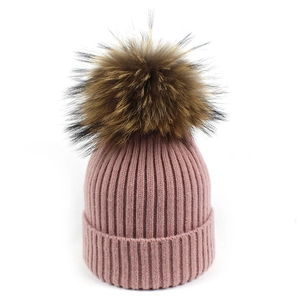 Detalle del gorro de punto acanalado rosa con un gran pompón de piel sintética suave