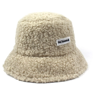 Close-up detail of cream lamb wool bucket hat featuring a white rectangular text label