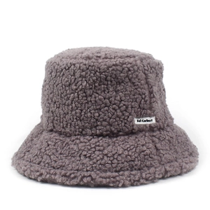 Detailed view of dark brown teddy plush fisherman hat with brand logo patch on side