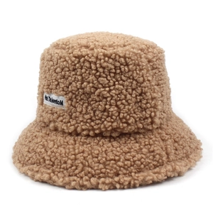 Detailed view of camel faux shearling fabric texture and woven brand label on the hat