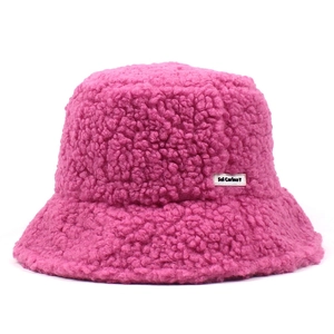 Detail of soft dark pink teddy fleece fabric and woven brand label on the bucket hat