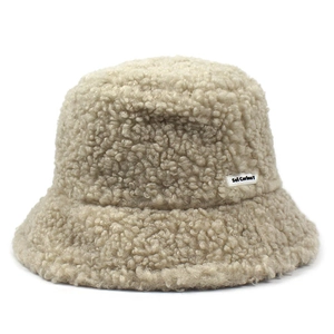 Detail shot of fluffy cream teddy fur bucket hat with embroidered logo tag and soft texture