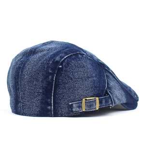 Close-up of washed denim beret featuring an adjustable vintage gold metal buckle