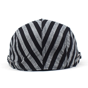Detail of adjustable metal buckle and textured striped fabric on a summer beret hat