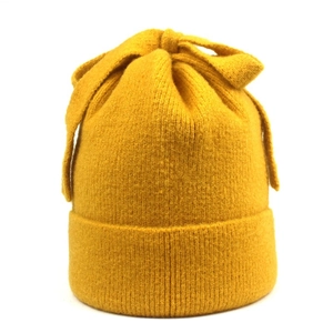 Detailed knit texture of ginger yellow winter beanie featuring a top bow decoration