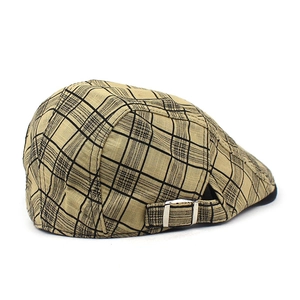 Detail of adjustable silver metal buckle and khaki plaid fabric on the newsboy cap