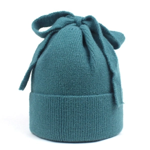 Detail of teal knit beanie featuring a large decorative bow and ribbed texture