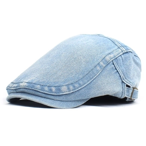 Detail view of light blue washed denim flat cap with adjustable bronze metal buckle