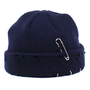 Close-up of navy blue knit beanie featuring punk style silver safety pins and metal rings