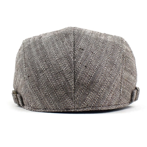 Detail view of herringbone patterned beret with adjustable bronze metal buckle