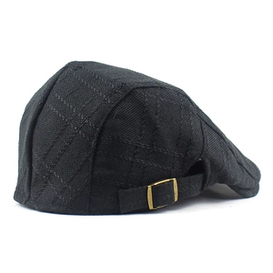 Detail view of black linen newsboy cap showing texture and gold adjustable metal buckle