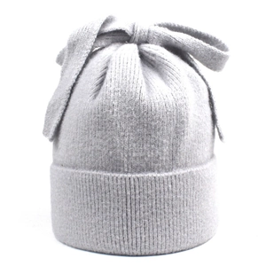 Detailed close-up of light gray knitted beanie with large bow accent and ribbed edge