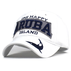 White cotton baseball cap with blue ARUBA embroidery and a shark patch on the brim