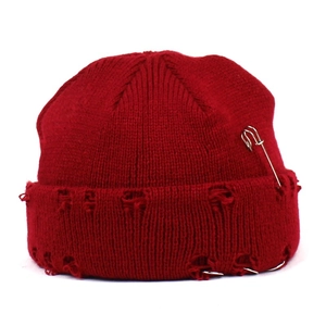 Distressed dark red knit beanie featuring stylish holes, a silver pin, and metal rings