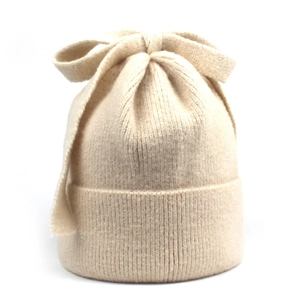Detailed close-up of a cream-colored ribbed knit beanie featuring a large decorative bow knot