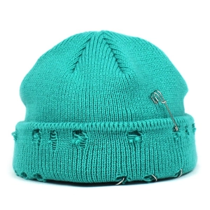 Detailed view of teal knit beanie featuring punk style safety pin and silver metal rings