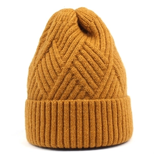 Close-up of mustard yellow knit beanie showing detailed cross-weave texture and ribbed cuff