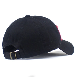 Detail view of adjustable metal buckle and red embroidery on a black cotton baseball cap