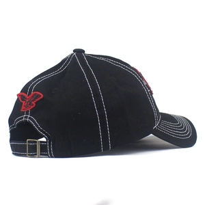 Detail view of the black baseball cap showing the white contrast stitching and red eagle embroidery